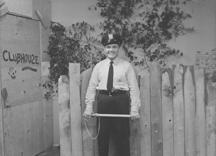 Ted Knight in police uniform on the clubhouse set.