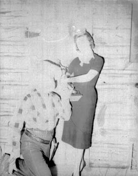 Windy Knight with a young woman holding a trophy on the log cabin set.